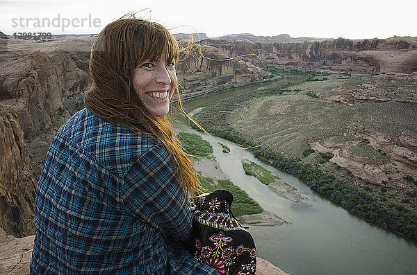 Lächelnde Frau am Grand Canyon sitzend