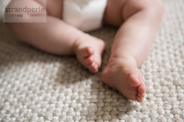 Nackte Füße des Babys auf dem Teppich