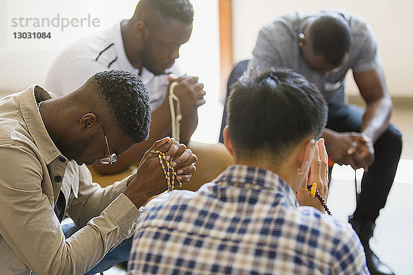 Männer beten mit Rosenkränzen in einer Gebetsgruppe