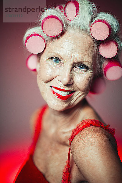 Porträt lächelnde  selbstbewusste ältere Frau mit Lockenwicklern im Haar
