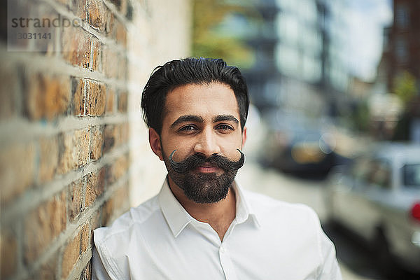 Porträt eines selbstbewussten jungen Mannes mit Schnurrbart auf einem Bürgersteig