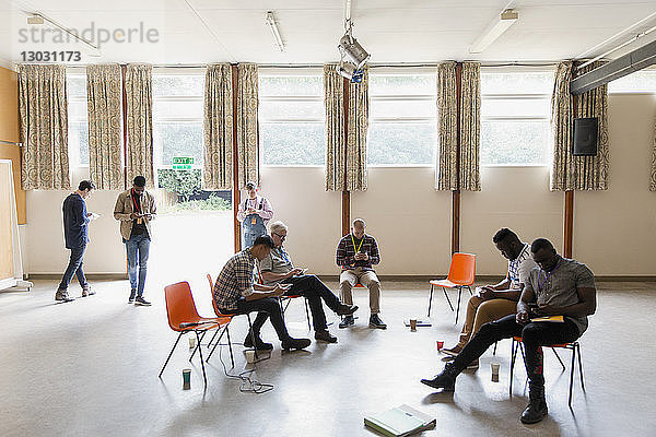 Wartende Männer  die Smartphones im Gemeindezentrum benutzen