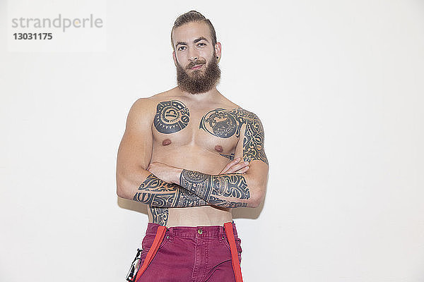 Porträt selbstbewusster  cooler männlicher Hipster mit nackter Brust und Tattoos