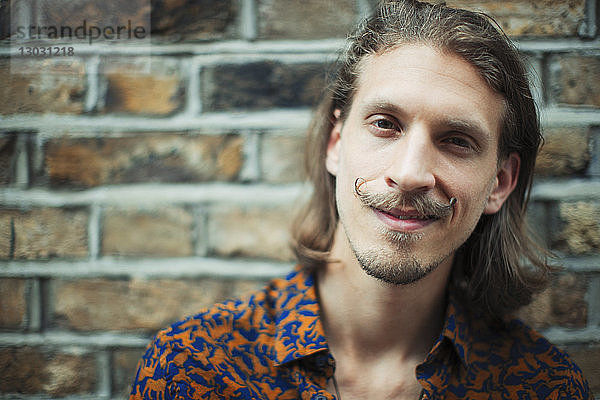 Porträt lächelnder  selbstbewusster junger männlicher Hipster mit Schnurrbart