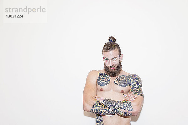 Porträt selbstbewusster männlicher Hipster mit nackter Brust und Tattoos