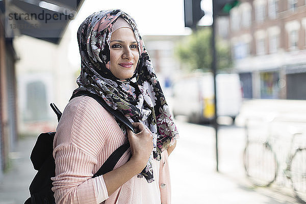 Porträt selbstbewusste Frau in geblümtem Hijab auf städtischem Bürgersteig