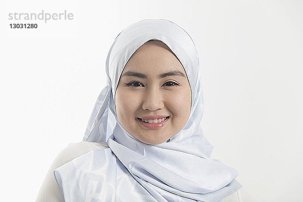 Porträt einer lächelnden  selbstbewussten jungen Frau  die einen blauen Hidschab aus Seide trägt