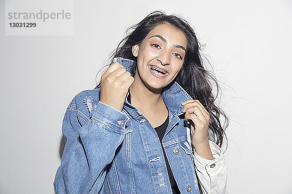 Porträt eines glücklichen  selbstbewussten Teenagers mit Hosenträgern und Jeansjacke