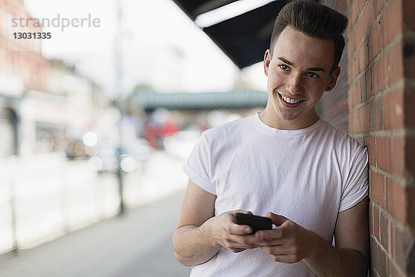 Jugendlicher benutzt Smartphone auf dem Bürgersteig