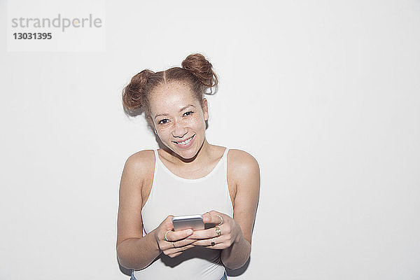 Porträt einer lächelnden  selbstbewussten jungen Frau  die eine SMS mit einem Smartphone schreibt