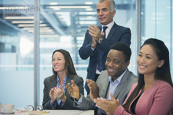 Geschäftsleute lächelnd und klatschend in Konferenzraum Sitzung