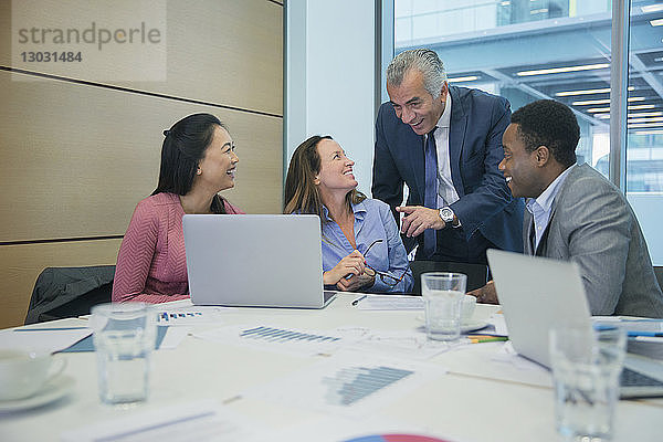Lächelnde Geschäftsleute mit Laptop im Konferenzraum