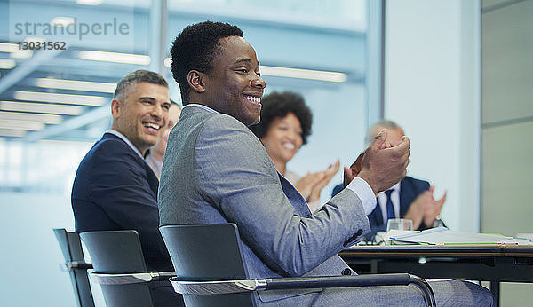 Lächelnder Geschäftsmann  der in einem Konferenzraum klatscht