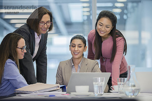Lächelnde Geschäftsfrauen mit Laptop im Konferenzraum