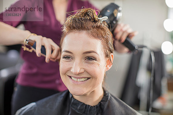 Friseur föhnt das Haar des Kunden im Salon