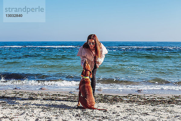 Stylische Frau mittleren Alters am Strand  die ihren Hund streichelt  Odessa  Odeska Oblast  Ukraine