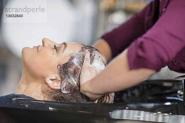 Friseur  der die Haare seiner Kunden im Salon wäscht