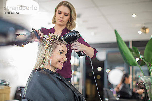 Friseur föhnt das Haar des Kunden im Salon