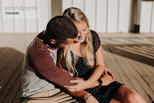 Romantischer Mann und Freundin sitzen auf der Veranda und umarmen sich