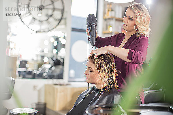 Friseur föhnt das Haar des Kunden im Salon