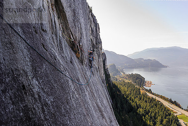 Junger männlicher Bergsteiger beim Klettern an einer Felswand  erhöhte Ansicht  The Chief  Squamish  Britisch-Kolumbien  Kanada