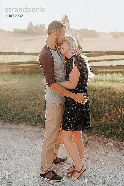 Romantischer Mann küsst auf ländlichem Feldweg seine Freundin auf die Stirn