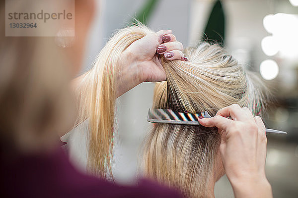 Friseur frisiert die Haare des Kunden im Salon