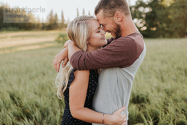 Romantischer Mann und Freundin umarmen sich im Feld aus langem Gras