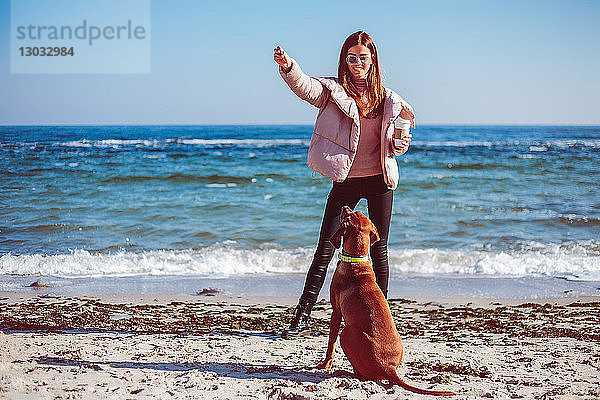 Mittlere erwachsene Frau am Strand beim Training ihres Hundes  Odessa  Odeska Oblast  Ukraine
