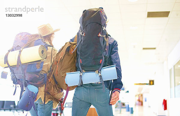 Junges Paar am Flughafen  Rucksäcke tragend  Rückansicht