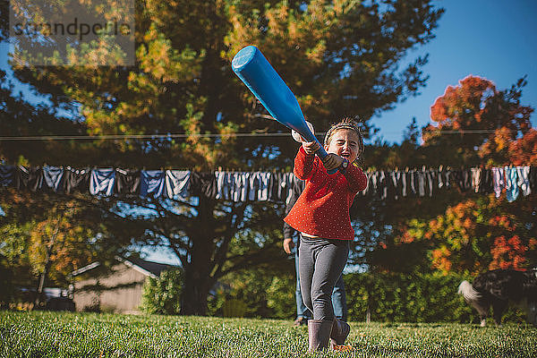 Mädchen schwingt Baseballschläger im Garten