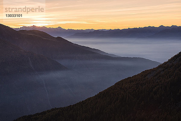 Silhouetten der Orobie-Alpen im Nebel des herbstlichen Sonnenuntergangs  Valmalenco  Valtellina  Lombardei  Italien