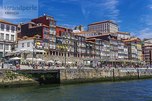 Traditionelle Häuser am Wasser im Stadtteil Ribeira am Fluss Douro mit Menschen am Ufer  Porto  Portugal