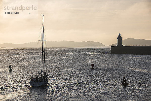 Segelboot auf dem Weg aus dem Hafen von St. Peter Port bei Sonnenaufgang  Guernsey  Kanalinseln  Vereinigtes Königreich