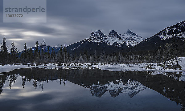 Kanadische Rockies an einem düsteren Tag  mit den Three Sisters über dem See  Alberta  Kanada
