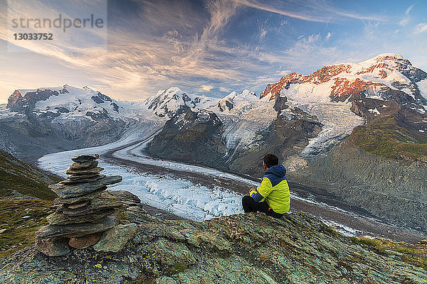 Wanderer auf einem Felsen sitzend mit Blick auf den Monte-Rosa-Gletscher  Zermatt  Kanton Wallis  Schweizer Alpen  Schweiz