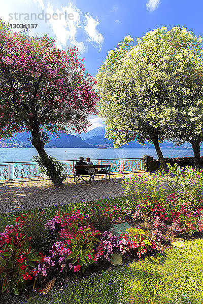 Zwei Personen sitzen auf einer Bank und schauen auf den See  Bellagio  Provinz Como  Comer See  Italienische Seen  Lombardei  Italien