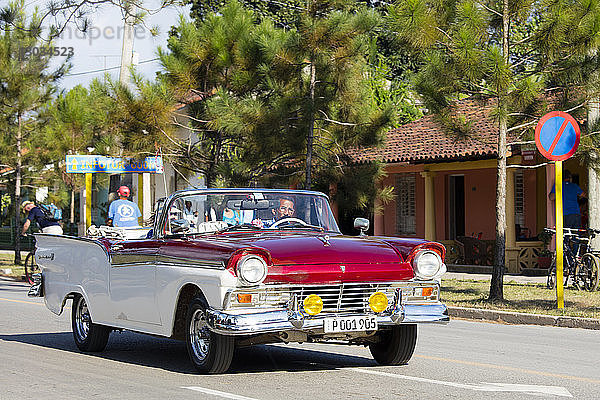 Rotes und weißes Cabrio-Oldtimertaxi auf der Hauptstraße in Vinales  UNESCO-Weltkulturerbe  Kuba  Westindien  Karibik