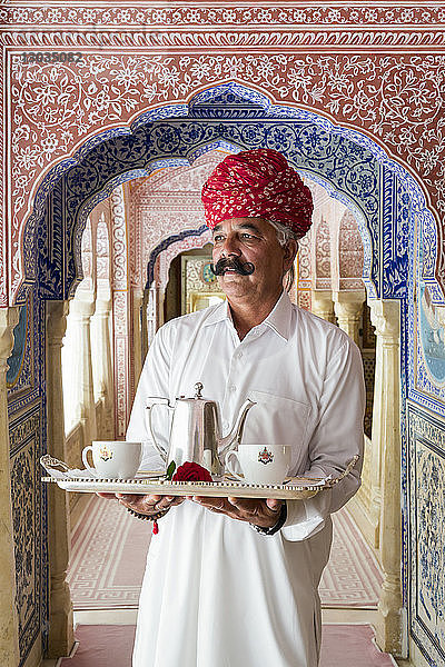 Kellner  der ein Teetablett in einem verzierten Durchgang trägt  Samode Palace  Jaipur  Rajasthan  Indien