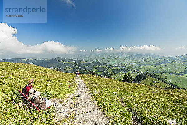 Menschen auf einer Bank im grünen Tal der Ebenalp mit Blick Richtung Appenzell und Schwende  Appenzell Innerrhoden  Schweiz
