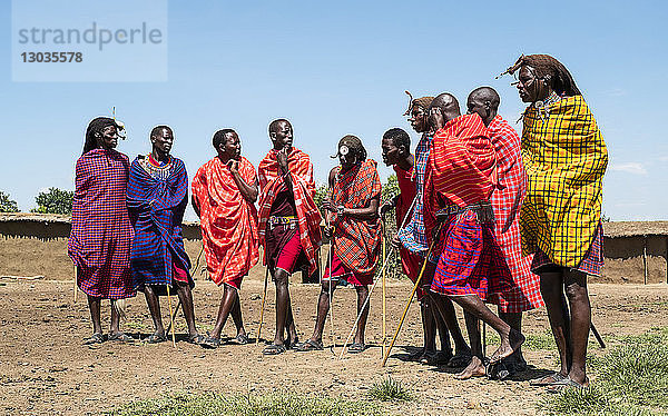 Mitglieder der Masai Mara singen Stammeslieder zur Begrüßung der Gäste in ihrem Dorf  Masai Mara National Reserve  Kenia  Ostafrika