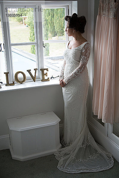 Braut schaut vor der Hochzeit aus dem Fenster