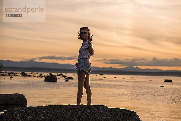 Junge Frau steht bei Sonnenuntergang auf einem Felsen  Porträt  Quadra Island  Campbell River  Kanada