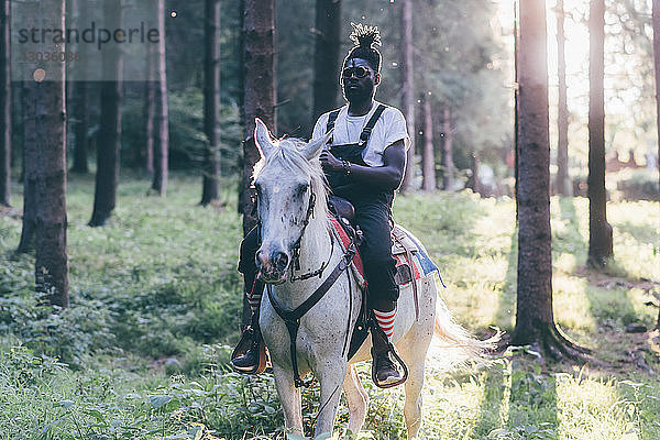 Kühler junger Mann reitet im sonnenbeschienenen Wald  Primaluna  Trentino-Südtirol  Italien