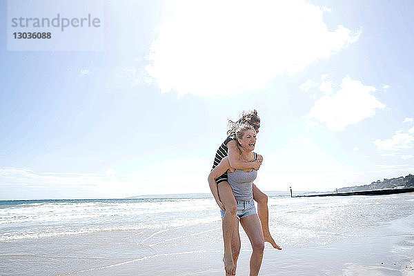 Schwestern spielen Huckepack am Strand