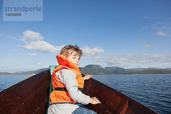 Junge  der von vorne vom Ruderboot aus zurückblickt  Aure  More og Romsdal  Norwegen