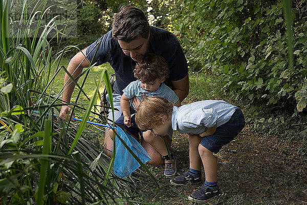 Vater und Kinder mit Fischernetz im Park