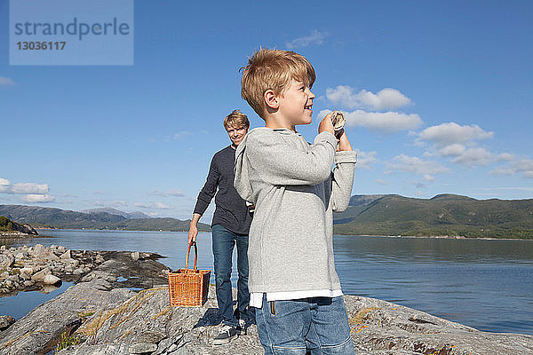 Junge und Vater tragen Korb über den Einlassfelsen  Aure  More og Romsdal  Norwegen
