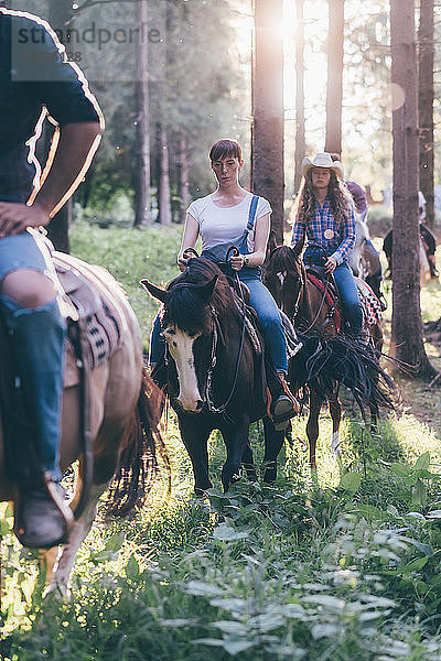Junge erwachsene Freunde reiten im sonnenbeschienenen Wald  Primaluna  Trentino-Südtirol  Italien
