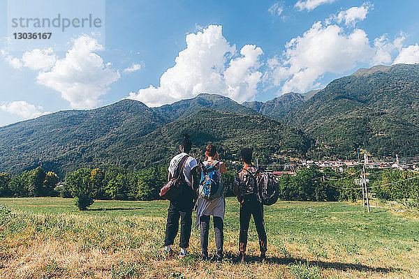 Drei junge Wanderfreunde mit Blick auf die Berge  Rückansicht  Primaluna  Trentino-Südtirol  Italien